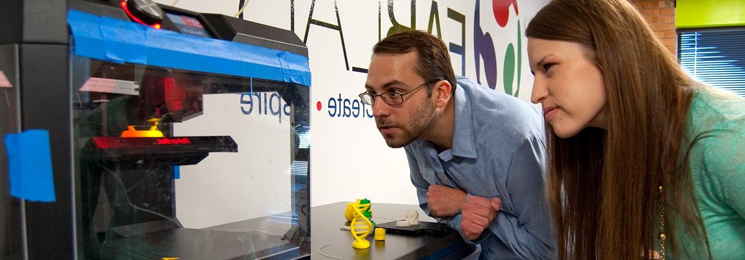 两个学生在实验室观看3D打印机